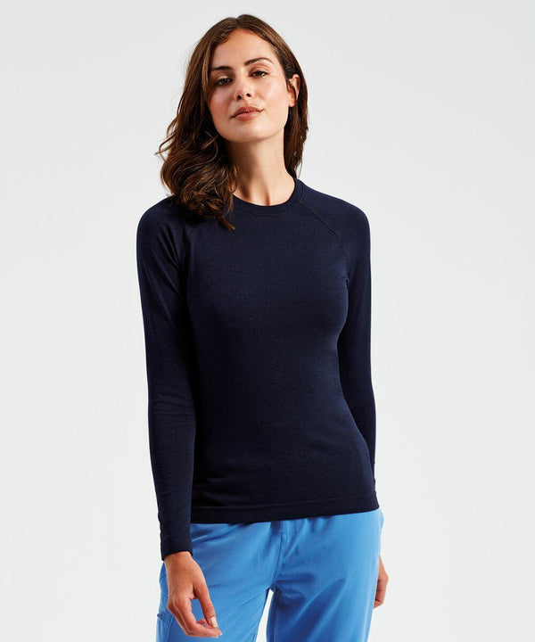 A woman with wavy brown hair wearing a dark long-sleeve top and blue pants stands against a plain background, showcasing the NN370 by Onna.