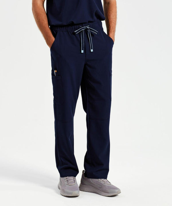A person wearing navy blue NN500 scrub pants by Onna with hands in pockets and gray sneakers stands against a plain background.