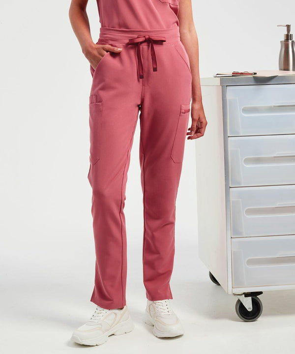 A person wearing Onna NN600 pink scrub pants with a drawstring, standing beside a rolling cart with drawers.