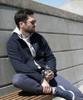 A man wearing sunglasses and casual clothing sits on a bench, holding a Nimbus NP15M.