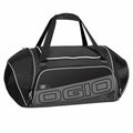 A black and gray duffel bag from Ogio, model OG021, with white accents, dual handles, and multiple zippered compartments.
