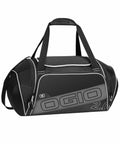 A black and gray duffel bag with the brand name "Ogio" and "OG022" printed on the side. It has dual handles and a shoulder strap.