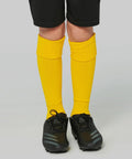 A pair of legs wearing yellow Kariban Proact PA016 soccer socks and black soccer cleats, with black shorts visible at the top.