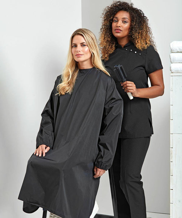 Two women in a hair salon, one seated wearing a black cape, the other standing holding a Premier PR117 round hairbrush.