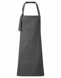 A plain, dark gray apron by Premier, featuring a halter neck and a side tie detail on the neck strap, Product Name: PR122.