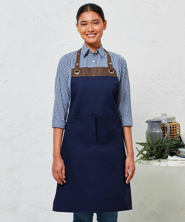 A person is standing and smiling, wearing a Premier PR123 with brown leather straps over a blue checkered shirt. A table with a teapot, plant, and decorative item is to the right.