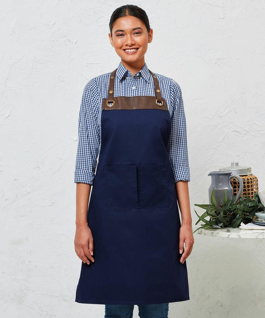A person is standing and smiling, wearing a Premier PR123 with brown leather straps over a blue checkered shirt. A table with a teapot, plant, and decorative item is to the right.