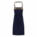 Introducing the Premier PR123, a stylish dark blue apron featuring striking brown leather straps and metal rivet details set against a crisp white background. This apron is designed with a convenient pocket on the front for added functionality.