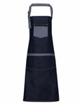 Premier's PR127 apron features a dark denim design, complete with an adjustable neck strap and two front pockets.
