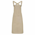 The PR129 apron by Premier is depicted against a white backdrop, featuring its beige color, cross-back straps, and large front pocket that highlight its simple and functional design.