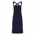 A Premier PR129 navy blue apron featuring crossed straps and a large front pocket, displayed flat against a white background.