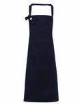 A Premier PR130 apron in navy blue featuring a halter neck strap and a bow detail on the top left corner. The design is sleek and simple with a straight silhouette.