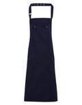 A Premier PR132 apron in navy blue featuring an adjustable neck strap and two front pockets.
