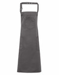Introducing the Premier PR132: This dark gray apron features an adjustable neck strap and two spacious front pockets. Its fabric boasts a clean and simple design, making it perfect for cooking or crafting activities.