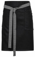 The Premier PR135 black skirt features delicate white stitching, a convenient front pocket, and is elegantly finished with a gray fabric belt tied at the waist.