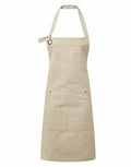The Premier PR137 is showcased on a white background, featuring a beige color with two front pockets and an adjustable neck strap. This versatile apron is ideal for cooking or crafts.