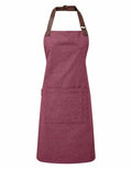 The Premier PR144 is a maroon apron featuring a spacious front pocket and an adjustable brown neck strap.