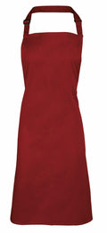 A plain, dark red PR150 apron by Premier featuring a neck strap with an adjustable buckle is showcased against a white background, displaying its full length and minimalist design without any additional patterns or embellishments.