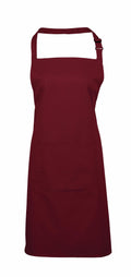 The Premier PR154 is a deep red apron featuring an adjustable neck strap and a front pocket.