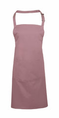 Introducing the Premier PR154 apron in a soft and durable plain mauve fabric, featuring an adjustable neck strap and a large front pocket. This versatile design is perfect for both cooking and crafting activities.
