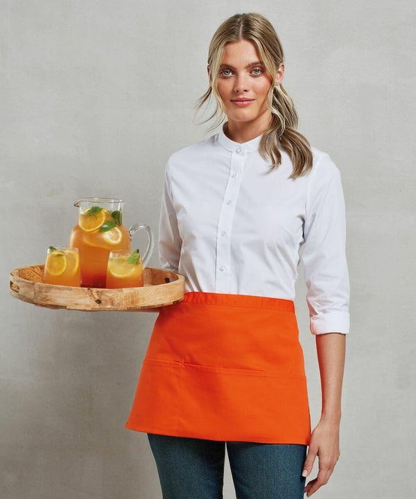 A person wearing a white shirt and orange apron is holding a wooden tray with a pitcher and glasses of orange beverage from Premier's PR155 collection.