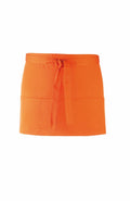 The Premier PR155 is an orange waist apron featuring a front tie and two pockets on the lower half, crafted from durable fabric ideal for kitchen or waitstaff applications.