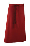 The Premier PR158, a red waist apron featuring a front pocket and tie straps, is showcased against a white background.