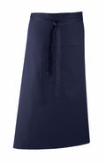 Premier's PR158 is a navy blue apron featuring a waist tie and front pocket. Displayed flat against a white background, the apron showcases its straightforward and practical design.
