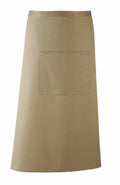 The PR158 apron by Premier is a plain beige design featuring a spacious front pocket. It offers a smooth and durable fabric, ideal for kitchen or craft activities, with its simple and classic appeal.