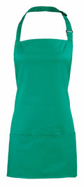 The Premier PR159 apron, featuring a solid green color, adjustable neck strap, and front pocket, is displayed against a white background.