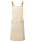 The aprons feature beige fabric with brown adjustable straps and brass fittings. Designed for practicality, they include a large front pocket and smaller side pocket. The sturdy, durable construction ensures long-lasting use.