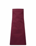 The Premier PR190 apron, featuring a plain maroon design with two front pockets and a neck strap, is displayed against a white background.