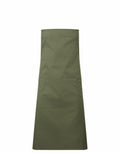 The Premier PR190 green apron, featuring adjustable neck straps and a large front pocket, is shown against a plain white background.