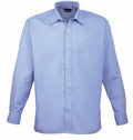 A Premier PR200 light blue long-sleeve button-up shirt, featuring a front pocket and a classic collar, displayed against a plain white background.