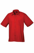 A short-sleeved, button-up Premier shirt (Product Name: PR202) in solid red, featuring a chest pocket and classic collar, displayed against a white background.