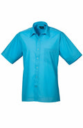 A Premier PR202 bright blue short-sleeved button-up shirt with a front pocket, displayed against a white background.