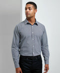 A person is standing against a plain background wearing a button-up, long-sleeve, checkered Premier PR220 shirt and dark pants, looking slightly to their left.