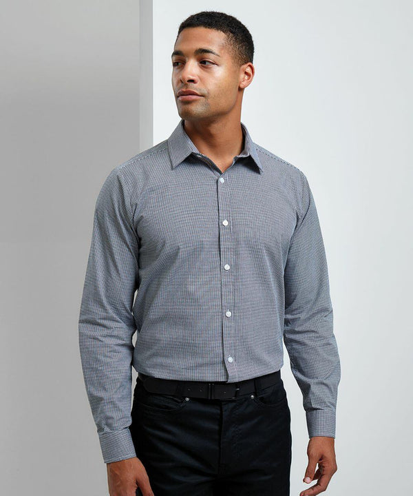 A person is standing against a plain background wearing a button-up, long-sleeve, checkered Premier PR220 shirt and dark pants, looking slightly to their left.