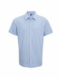 Premier's PR221: A light blue short-sleeve button-up shirt featuring a pointed collar, showcased against a white background.