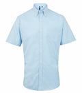 The Premier PR236 is a light blue button-up short-sleeve shirt featuring a chest pocket and a button-down collar, shown against a plain white background.