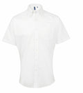 The Premier PR236 is a white short-sleeved button-up shirt with a classic collar and front pocket, elegantly showcased against a plain background. This wrinkle-free shirt is versatile, perfect for both formal and casual occasions.