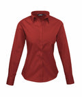 The Premier PR300 is a red long-sleeve button-up shirt with a collar, showcased against a white background. It offers a tailored fit, with curves at the waist and long cuffs at the wrists.