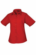 A Premier PR302 plain red short-sleeve button-up shirt with a collar, displayed on a white background.