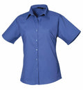 The Premier PR302 is a short-sleeved, button-up blue shirt with a collar, displayed against a white background.