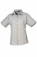 The Premier PR302 shirt is a beige short-sleeve button-up with a pointed collar, showcased against a white background.