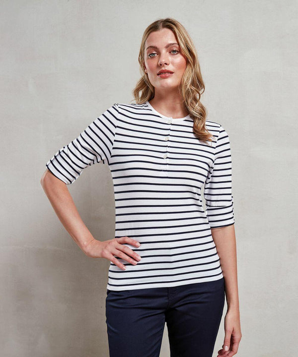 A person wearing a white PR318 shirt with black horizontal stripes and dark pants from Premier stands against a plain background, with one hand on their hip.