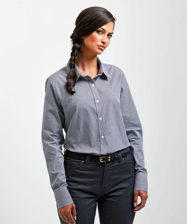 A woman with long, dark hair in a braid wears a light blue Premier PR320 button-up shirt and dark pants. She stands with her hands relaxed at her sides and looks slightly to her left.