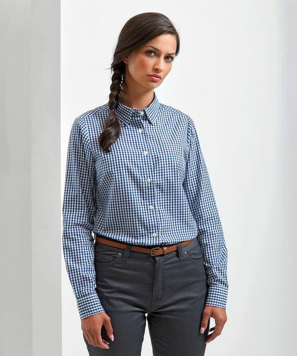 A woman with long braided hair is wearing a Premier PR352 blue checkered shirt and dark gray pants, standing against a plain white background.