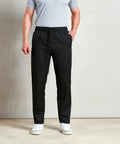 A person wearing a light gray Premier PR554 polo shirt, black drawstring pants, and white sneakers stands against a plain background.