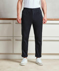 A person stands in a kitchen, wearing a white shirt, Premier PR557 drawstring pants, and white sneakers. The Premier PR557 pants are slightly rolled up at the ankles.